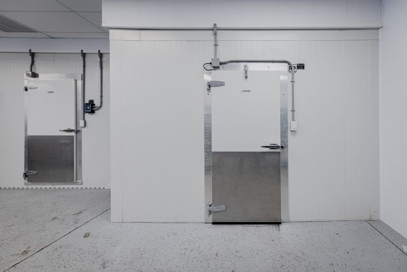 Portes de chambres froides industrielles blanches avec poignées métalliques dans un espace propre et bien éclairé