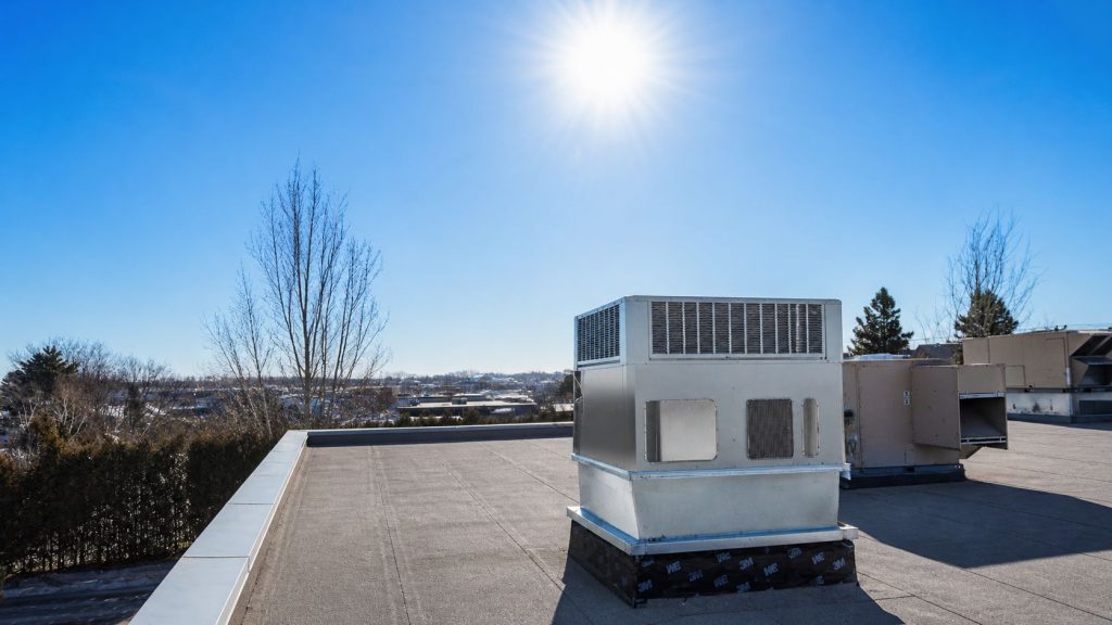 Unité de système de chauffage, ventilation et climatisation (CVC) sur un toit plat sous un ciel clair avec le soleil brillant