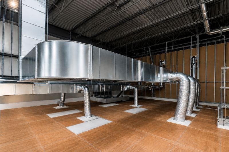 Conduits d'aération métalliques dans une installation HVAC industrielle sur un sol en bois avec plafond en métal