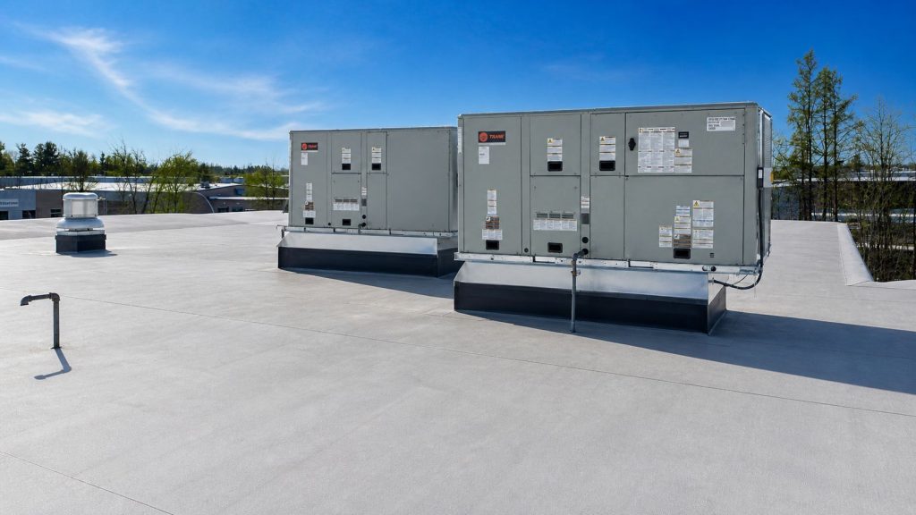 Unités de système de climatisation sur le toit d'un bâtiment commercial sous un ciel bleu clair