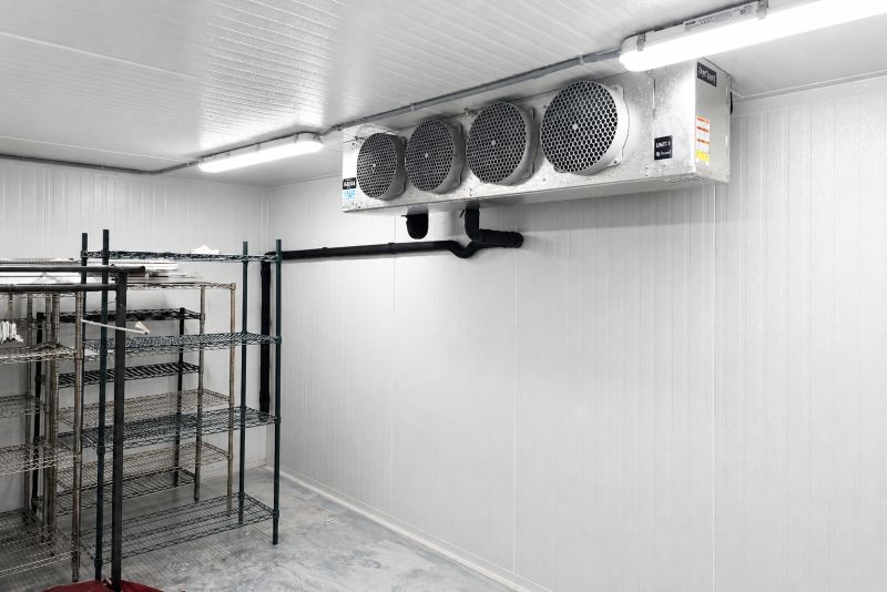 Chambre froide vide avec étagères métalliques et système de refroidissement industriel au plafond