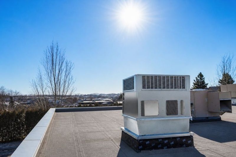 Un système de ventilation sur un toit plat sous un ciel bleu clair avec le soleil brillant