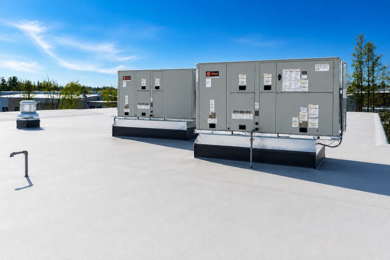 Unités de systèmes de chauffage, ventilation et climatisation (CVC) installées sur un toit plat d'un bâtiment commercial sous un ciel bleu clair