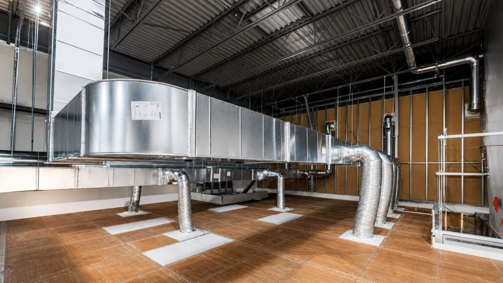 Système de conduits métalliques pour la ventilation dans un espace industriel avec plafond ouvert et plancher en bois